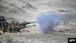 美国和菲律宾海军陆战队2024年5月6日在吕宋岛西北海岸拉瓦格的一条沙丘上发射M198的155毫米榴弹炮，这是美菲年度“肩并肩”联合军事演习的一部分。