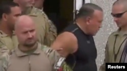Cesar Sayoc, in dark shirt, who was arrested during an investigation into a series of parcel bombs, is escorted from an FBI facility in Miramar, Fla., Oct. 26, 2018, in a still image from video.