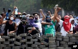 Protesters yell from behind the roadblock they erected as they face off with security forces near the University Politecnica de Nicaragua in Managua, Nicaragua, April 21, 2018.