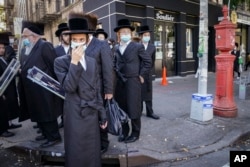 Sejumlah anggota komunitas Yahudi Ortodoks di sebuah pojokan jalan di kawasan Borough Park di Brookly, New York, 11 Mei 2021. (Foto: John Minchillo/AP Photo)