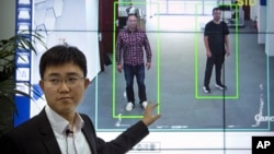 In this Oct. 31, 2018, photo, Huang Yongzhen, CEO of Watrix, demonstrates the use of his firm's gait recognition software at his company's offices in Beijing. 