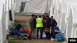 An employee of ORS, a subsidiary of a Switzerland-based enterprise managing Austria's migrant camps, is seen talking to residents of the reception center in Traiskirchen, Austria. (Photo - VOA video grab)