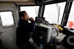 Whale-watching boat captain Masato Hasegawa speaks with other boats in order to look for whales in the sea near Rausu, Hokkaido, Japan, July 1, 2019.