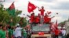 Supporters of the National League for Democracy (NLD) party on a motorcade pass supporters of the opposition Union Solidarity and Development Party (USDP), seen at left, during a campaign in Wundwin, near Mandalay on September 19, 2020. (Photo by Kyaw The