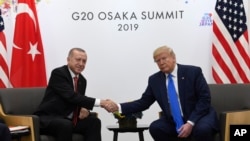 Presiden Donald Trump berjabat tangan dengan Presiden Turki Recep Tayyip Erdogan di Osaka, Jepang, 29 Juni 2019. (Foto: Associated Press)
