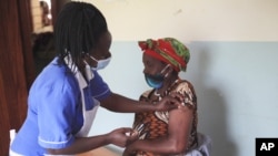 FILE - A nurse administers the AstraZeneca COVID-19 vaccine to a woman at the Butanda Health Centre III in western Uganda, April 27, 2021.