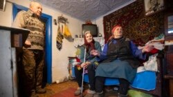 Kateryna Shklyar, right, speaks to The Associated Press as her husband, Dmytro, left, and Halyna Moroka gather near her at her house in the village of Nevelske in eastern Ukraine, on Dec. 10, 2021.