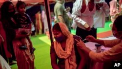 In this Wednesday, Sept. 29, 2021 file photo, a woman reacts as a health worker inoculates her during a vaccination drive against COVID-19 in New Delhi, India. (AP Photo/Altaf Qadri, file)