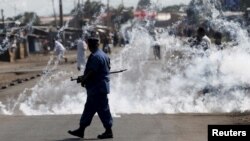 FILE - A policeman walks away after throwing a teargas canister at protesters rallying against Burundi President Pierre Nkurunziza and his bid for a third term, in Bujumbura, Burundi, June 2, 2015.