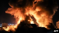 The sky is lit by an explosion above buildings in Gaza City as Israeli forces shell the Palestinian enclave, early May 18, 2021.