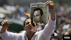 Seorang demonstran membakar poster mantan Presiden Hosni Mubarak di Lapangan Tahrir, Kairo (1 Juli 2011).