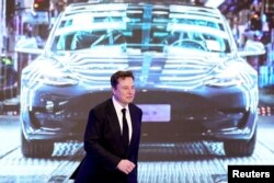 CEO Tesla Inc Elon Musk berjalan di samping layar yang menunjukkan gambar mobil Tesla Model 3 buatan Tesla China di Shanghai. (Foto: Reuters)