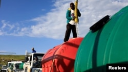 A man refills water in a jojo tank loaded in one of the trucks hired to deliver emergency water to residents, at Blue Gum Bush in Qwaqwa, in the Free State province, South Africa, February 5, 2020. Picture taken February, 5, 2020. REUTERS/Siphiwe Sibeko -
