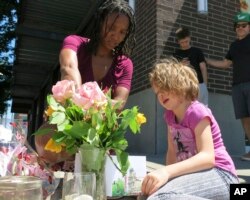 Angel Sauls (left) helps her stepdaughter, Coco Douglas, arrange a sign and some painted rocks she made for a memorial in Portland, Ore., May 27, 2017, for two bystanders who were stabbed to death Friday.