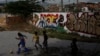 FILE - Children play soccer outside as they wait for the inauguration of a soccer pitch at the entrance of Jacarezinho shantytown in Rio de Janeiro, Brazil.