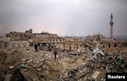 A member of forces loyal to Syria's President Bashar al-Assad stands with a civilian on the rubble of the Carlton Hotel, in the government controlled area of Aleppo, Syria, Dec. 17, 2016.
