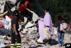 A man is given personal belongings after rescuers recovered the body of a woman from the collapsed house, in Amatrice, Aug. 26, 2016.