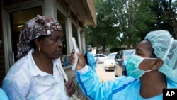 A woman has her temperature taken by a Health worker before visiting a relative at a public hospital, in Harare, Zimbabwe, March 21, 2020. 