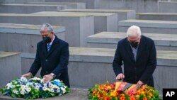 German President Frank-Walter Steinmeier, right, and the Speaker of Israel's Parliament Mickey Levy arrange wreaths on one of the concrete slabs of Berlin's Holocaust Memorial, Jan. 27, 2022, marking International Holocaust Remembrance Day.