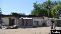 FILE - Women walk by homes destroyed by Boko Haram militants in Bama, Borno State, Nigeria.