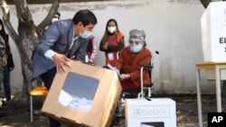 Andres Arauz, presidential candidate of the United for Hope alliance, lifts the ballot box so his grandmother, Flor Celina Galarza, can vote during presidential and legislative elections in Quito, Ecuador, Feb. 7, 2021. 