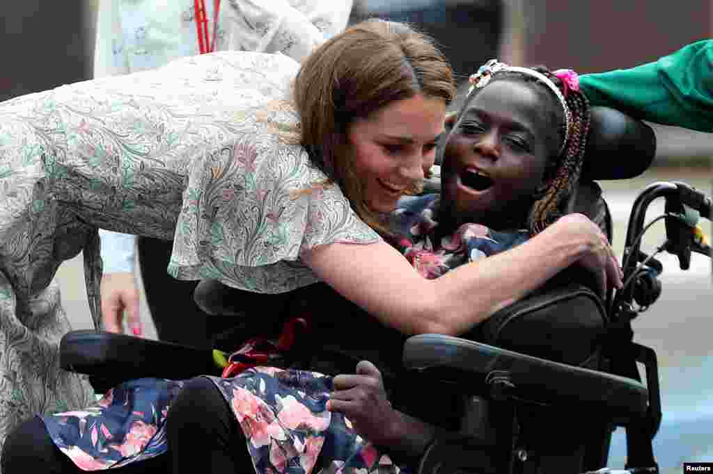 Britain&#39;s Catherine, Duchess of Cambridge, hugs a girl in a wheelchair as she joins a photography workshop with Action for Children in Kingston upon Thames.
