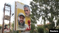 A poster depicting assassinated Hezbollah military commander Imad Moughniyeh and the late Iran's Quds Force top commander Qassem Soleimani is seen in the village of of Ain Qana, Lebanon, Sept. 22, 2020. 