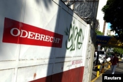 FILE - A man walks past the corporate logo of Odebrecht in a construction site in Caracas, Venezuela, Jan. 26, 2017.