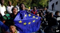 Des migrants, dont un portant le drapeau de l'Union européenne, célèbrent leur arrivée dans l'enclave espagnole de Ceuta après avoir franchi une clôture, le 17 février 2017.