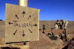 FILE - U.S. Marines fill sandbags on the frontlines of a U.S. Marine Corps base, near a cardboard sign reminding everyone that Taliban forces could be anywhere, in southern Afghanistan, Dec. 1, 2001.