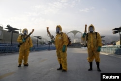 FILE - Municipal workers wait before spraying insecticide at Sambodrome in Rio de Janeiro, Brazil, Jan. 26, 2016.