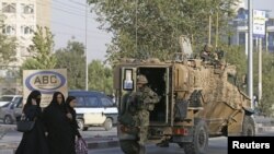 کابل میں ایک حملے کے بعد جائے واقعہ پر تعینات برطانوی فوجیوں کے نزدیک سے افغان خواتین گزر رہی ہیں۔