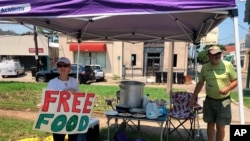 Joyce and Dave Thomas offer free meals, cooked up by one of their neighbors, along the Carrollton streetcar tracks in New Orleans, Sept. 2, 2021. Much of the city was without power and many restaurants and individuals were trying to help the community wit