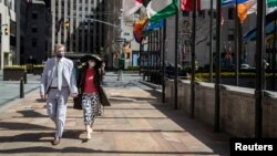 A couple wearing protective masks is seen as the outbreak of the coronavirus disease (COVID-19) continues in the Manhattan borough of New York City, New York, U.S., April 12, 2020. REUTERS/Jeenah Moon