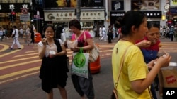 Para turis dari China daratan memakan jajanan pinggir jalan di pusat kota Hong Kong. (Foto: Dok)