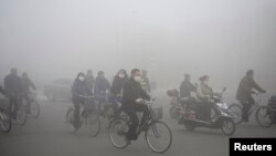 Warga setempat melintasi jalanan yang tertutup kabut tebal akibat polusi di Daqing, provinsi Heilongjiang (21/10).