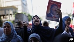 Para pendukung Presiden terguling Mohamed Morsi meneriakkan slogan dan memegang poster mantan presiden tersebut dalam protes di Lapangan Giza, Mesir (23/8).