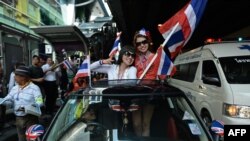 Thai anti-government protesters wave national flags as they follow march through streets of Bangkok, Dec. 20, 2013.