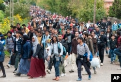 FILE - Migrants walk along a street after they arrived by train in Hegyeshalom, at the Austrian border, 169 km west of Budapest, Hungary, Oct. 7, 2015.