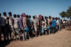 FILE - Ethiopian refugees who fled the Ethiopia's Tigray conflict wait in a line for the food distribution at the Um Rakuba refugee camp in Sudan's eastern Gedaref state, Dec. 12, 2020.