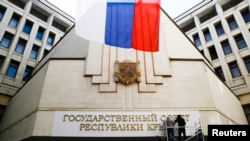 Workers put up a new sign reading "State Council of the Crimean Republic" at the parliament building in Simferopol, March 19, 2014.