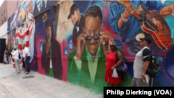 Spectators admire the new MuralsDC mural on the side of Ben's Chili Bowl.