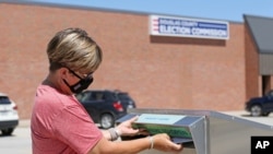 A woman drops her application for a mail-in ballot at the Douglas County Election Commission office in Omaha, Nebraska, Aug. 19, 2020. 