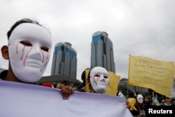Para wartawan mengenakan topeng saat mengikut pawai Hari Buruh di Museum Nasional (Monas), Jakarta, 1 Mei 2019. (Foto: Reuters)