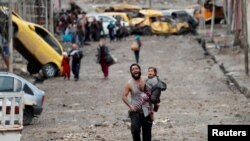 Un homme pleure en portant sa fille en marchant dans une partie de Mossoul contrôlée par l'État islamique vers des soldats des forces spéciales irakiennes lors d'une bataille à Mossoul, en Irak, le 4 mars 2017.
