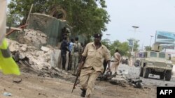 Petugas keamanan Somalia memeriksa lokasi serangan di sekitar gedung parlemen di Mogadishu (24/5).