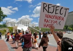 Protesters hold signs and march in front of the State Capitol across the street from the U.S. 4th Circuit Court of Appeals in Richmond, Virginia, May 8, 2017.
