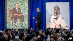 L'ancien président Barack Obama, au centre, est sur scène lors du dévoilement des portraits officiels du couple Obama à la National Portrait Gallery du Smithsonian, le 12 février 2018, à Washington.