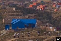 Rohingya refugees who were staying in a no-man's land at Bandarban at the border between Myanmar and Bangladesh carry their belongings to new locations after arriving at Balukhali refugee camp, 50 kilometers (32 miles) from Cox's Bazar, Bangladesh, Jan. 24, 2018.