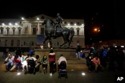 Residents sent running into the street after a magnitude-8.3 earthquake sit next to an equestrian statue in the main square of Santiago, Chile, Sept. 16, 2015.